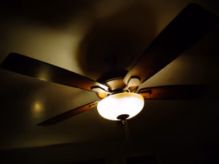 Wood-bladed ceiling fan with its light on